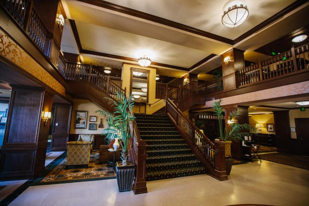 The grand lobby of the Hotel Julien, with a sweeping dark wood staircase, golden pendant lighting, and ornate balcony railings